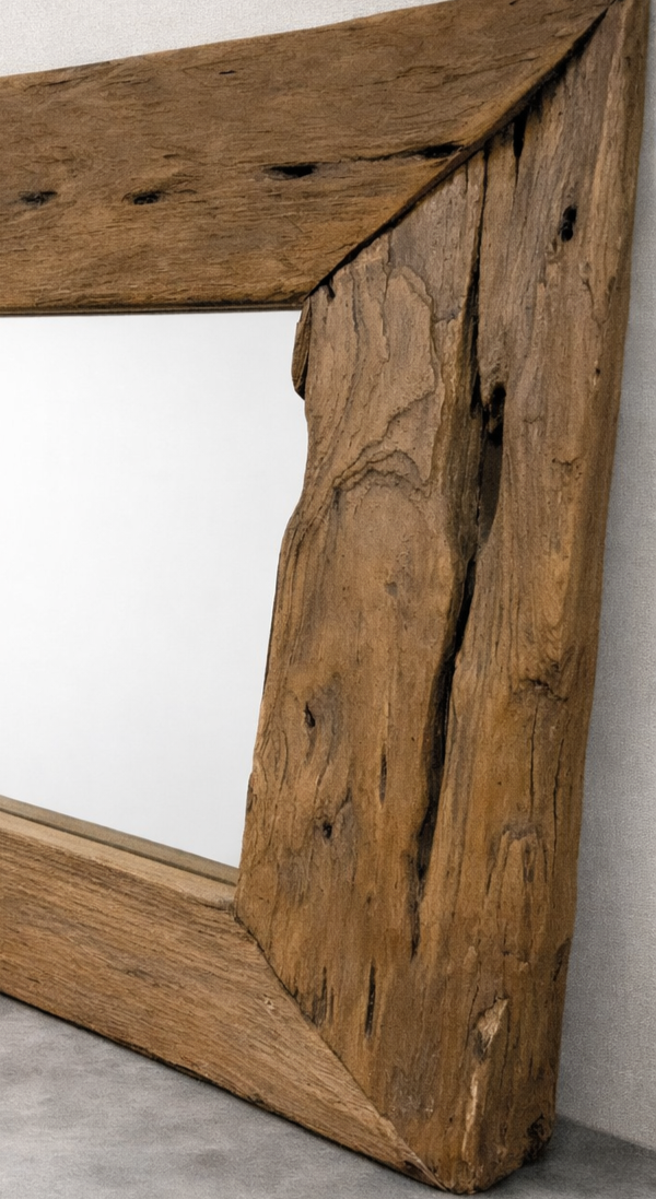 Close-up of a rustic wooden mirror frame against a linen wall.