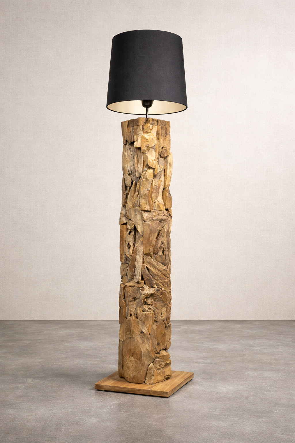 Rustic wooden floor lamp with a dark shade stands on the concrete floor of a studio.