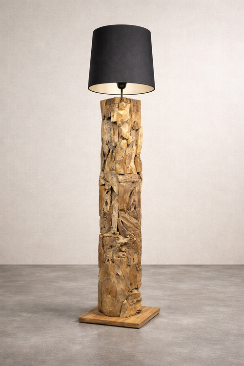 Rustic wooden floor lamp with a dark shade stands on the concrete floor of a studio.