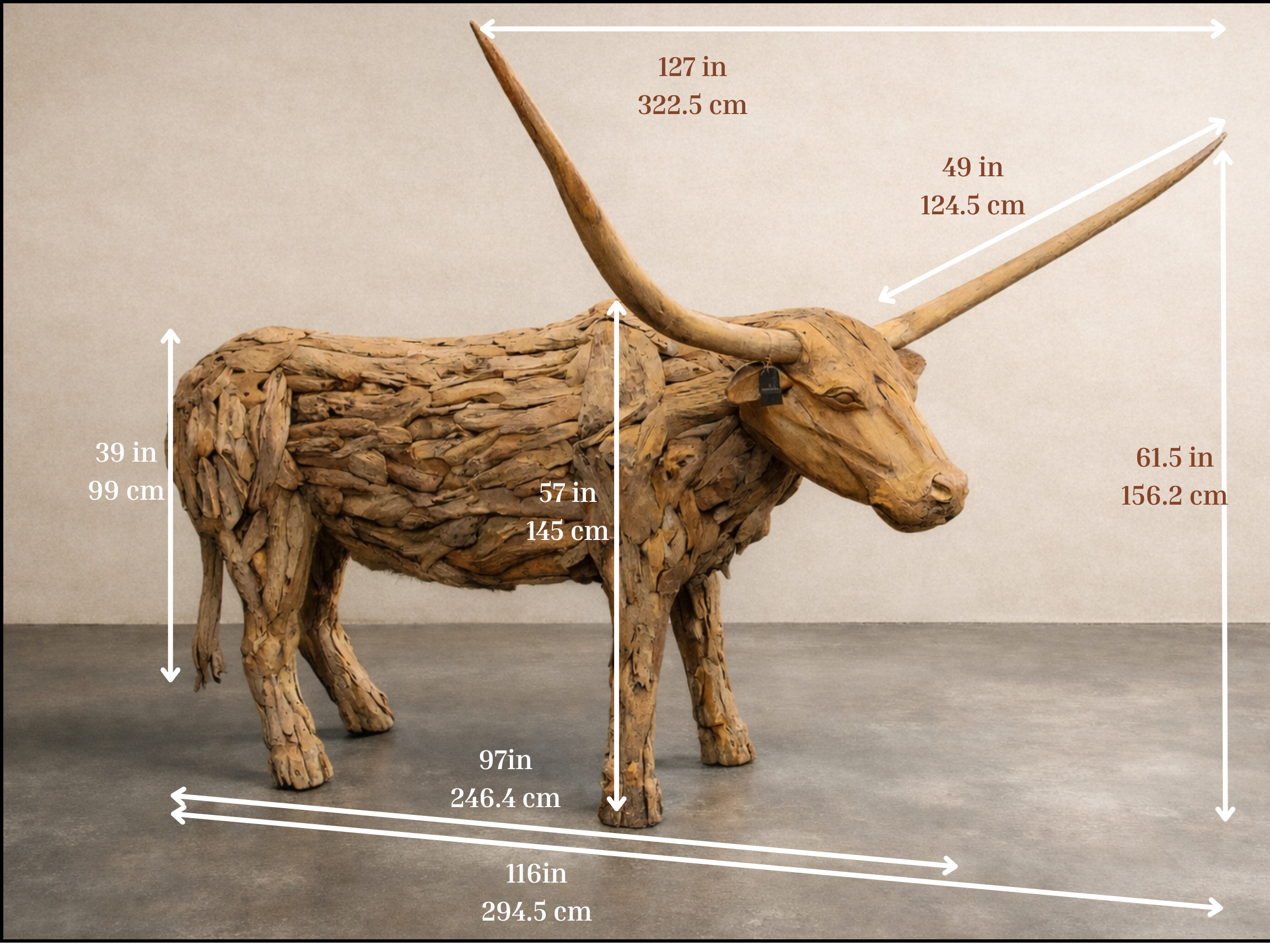 Life-size longhorn sculpture made from reclaimed teak wood, shown in a studio on a concrete floor. Natural layered wood texture, wide curved horns, and annotated dimensions indicating its large scale.