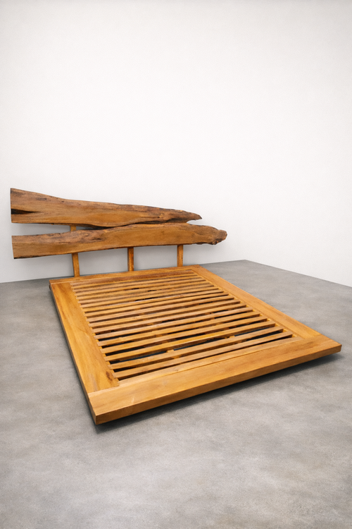 Handcrafted wooden platform bed with a low-profile slatted base and a sculptural live-edge headboard made from two natural wood slabs, photographed in a minimalist studio with smooth concrete floor and soft linen-colored wall.